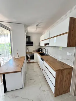 a kitchen with white cabinets and a wooden counter top at Sea apartment in Burgas City