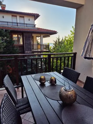 a wooden table on a balcony with chairs and a tableablish at Eve Santa Marina Sea View Apartment - sea, pools, relax in Sozopol