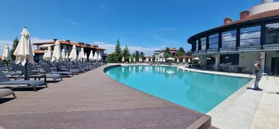 a swimming pool with chairs and umbrellas next to a building at Eve Santa Marina Sea View Apartment - sea, pools, relax in Sozopol