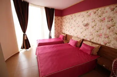 two beds in a room with pink sheets at Семеен Хотел Идън in Sveti Vlas