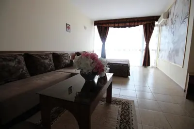 a living room with a couch and a table with flowers at Семеен Хотел Идън in Sveti Vlas
