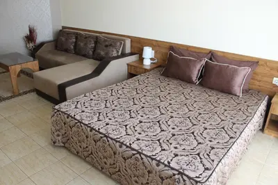 a bedroom with a large bed and a couch at Семеен Хотел Идън in Sveti Vlas