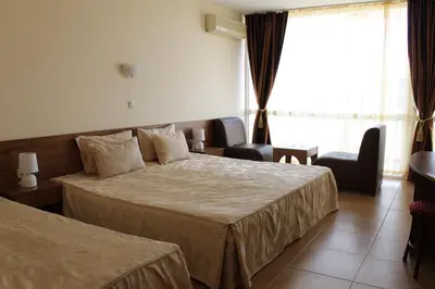 a hotel room with two beds and a desk at Семеен Хотел Идън in Sveti Vlas