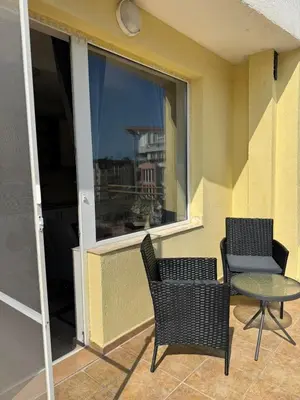 a balcony with two chairs and a table and a window at Студиа Осака in Sunny Beach