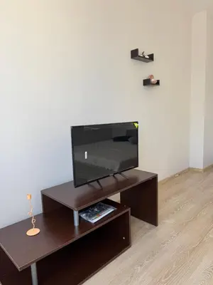 a flat screen tv sitting on a wooden entertainment center at Студиа Осака in Sunny Beach