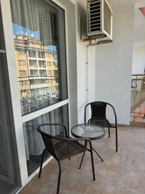 a balcony with two chairs and a table and a window at Студиа Осака in Sunny Beach