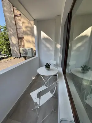 a small white table and chair in a room with a window at Magnoliya residence in Burgas City