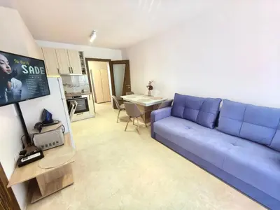 a living room with a blue couch and a kitchen at Sunny Dream Family Apartment in Sunny Beach