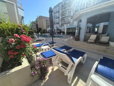 a patio with chairs and umbrellas and flowers at Sunny Dream Family Apartment in Sunny Beach