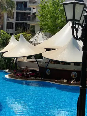 a boat with umbrellas next to a swimming pool at Schöne Ferienwohnung im Harmony Suites Monte Carlo in Sunny Beach