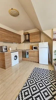 a kitchen with a white refrigerator and wooden cabinets at Уютно студио до центъра на Бургас in Burgas City
