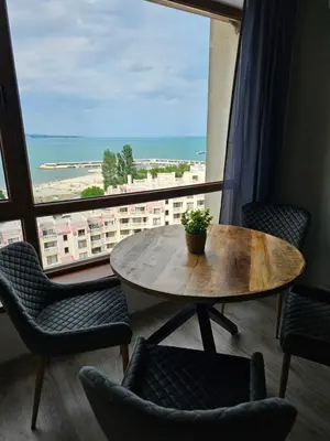 a table and chairs in a room with a large window at Comfy Flat Sea View & Strong Wi-Fi in Varna City