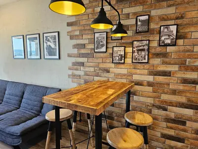 a table and stools in a room with a brick wall at Comfy Flat Sea View & Strong Wi-Fi in Varna City