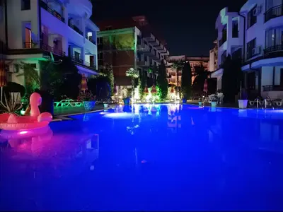 a swimming pool at night with a swan in the middle at Aura Blu Studio in Sunny Beach