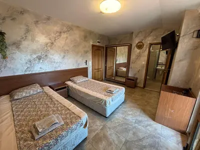 a hotel room with two beds and a mirror at Стая за гости - 1 in Sozopol