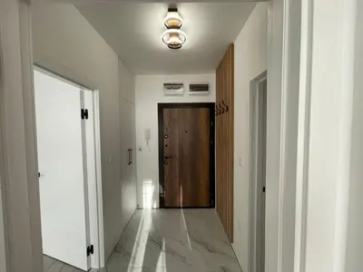 a hallway with a wooden door and a hallway with white walls at Сарафово in Burgas City