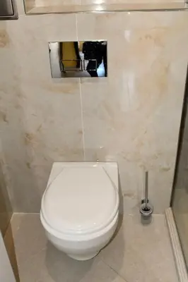 a white toilet in a bathroom with a picture on the wall at Anvers Apartments in Sozopol