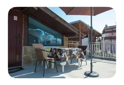 a table with chairs and an umbrella on a balcony at Guesthouse Christina in Varna City