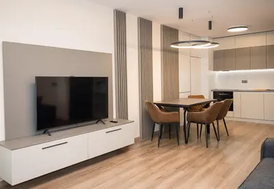 a living room with a table and a large television at Exclusive Central Varna Apartment - 2 Beds and Parking by Flat Mаnаger in Varna City