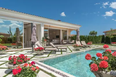 a house with a swimming pool with red flowers at Villa Dolce Vita in Sunny Beach