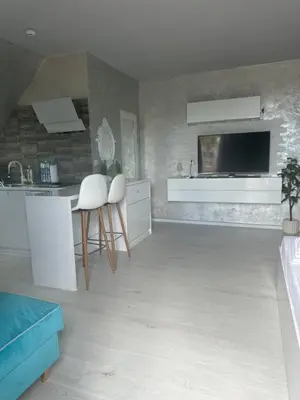 a living room with a kitchen with a tv on the wall at Residensia Bahami in Sunny Beach