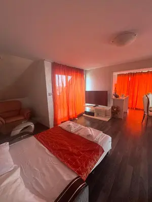a bedroom with a bed and a tv and orange curtains at Residensia Bahami in Sunny Beach