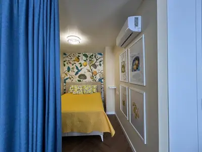 a small bedroom with a yellow bed with a blue curtain at Bayview Family 2 in Burgas City