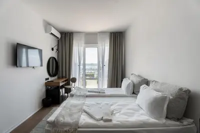 a white bedroom with a bed and a window at Hotel Sozopol 99 in Sozopol