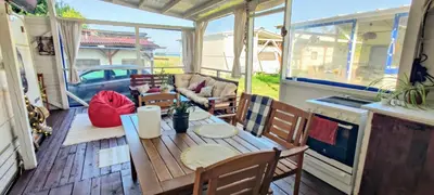 a screened in porch with a table and chairs at Яката Каравана in Kiten