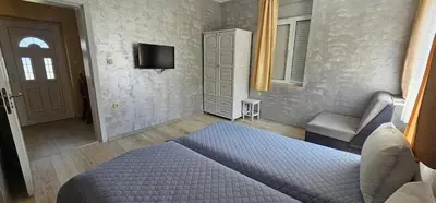 a bedroom with a bed and a couch and a tv at Victoria guest house in Obzor