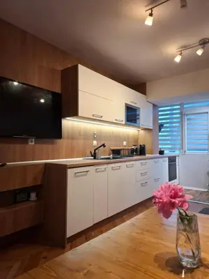 a kitchen with white cabinets and a tv on the wall at Accommodation apartment MARGARITA in Burgas City
