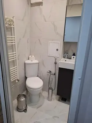 a white bathroom with a toilet and a sink at Accommodation apartment MARGARITA in Burgas City