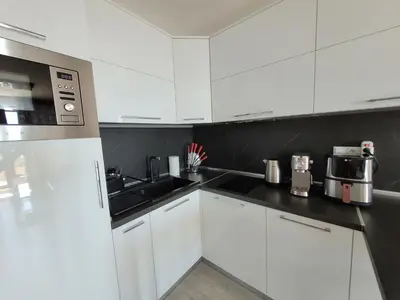 a kitchen with white cabinets and a black counter top at Millenium II B34 in Sveti Vlas