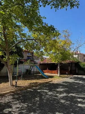 a playground with a slide and a tree at Benadi Guest House in Burgas City