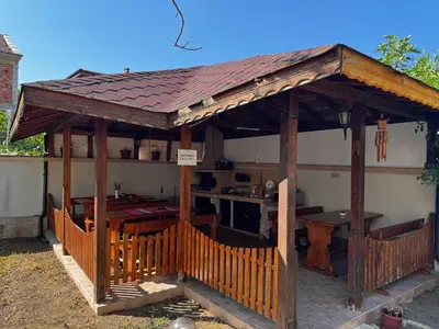a wooden gazebo with a table and a kitchen at Benadi Guest House in Burgas City