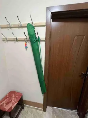 a green umbrella hanging on a wall next to a door at Laguna 3 минуты до моря in Pomorie