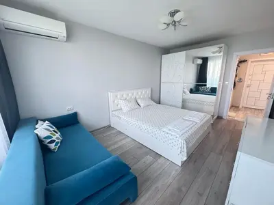 a bedroom with a white bed and a blue couch at Lazur Sea Home Burgas 2BD in Burgas City