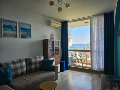 a living room with a couch and a large window at 2BR Sea Sunrise View Apartment Happy Place in Chernomorets