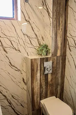 a bathroom with a toilet and a marble wall at Конакъ Войнов in Yasna Polyana