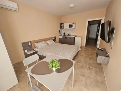 a bedroom with a bed and a table and a tv at Апартаменти Кастро2-Castro Apartments2 in Tsarevo