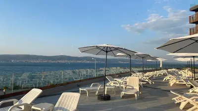 a row of white chairs and umbrellas on a patio at PARADISO B 410 Studio with SEA VIEW in Nesebar