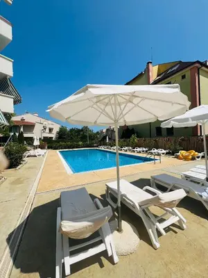 two chairs and an umbrella next to a pool at GREEN PARADISE apartments in Sveti Vlas