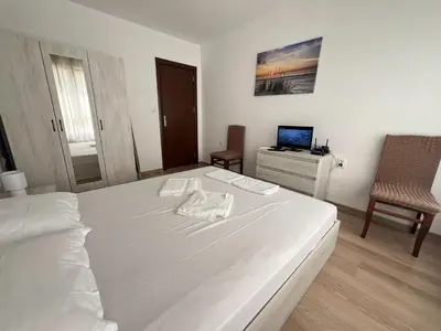 a bedroom with a large white bed and a chair at OKOLCHITSA - Stylish and Cozy Apartment in Varna City