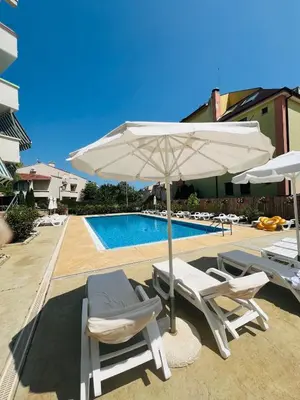 two chairs and an umbrella next to a pool at Green Paradise apartments in Sveti Vlas