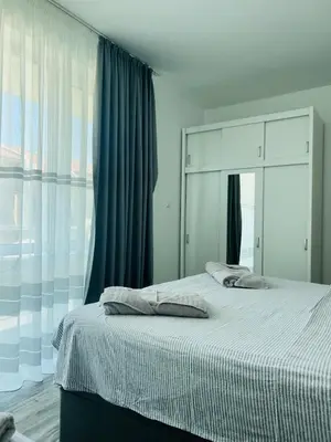 a bedroom with a large bed with blue curtains at Green Paradise apartments in Sveti Vlas