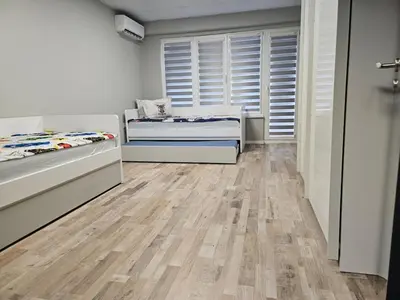 a bedroom with two beds and wooden floors at Central Flat, Close to the beach in Burgas City