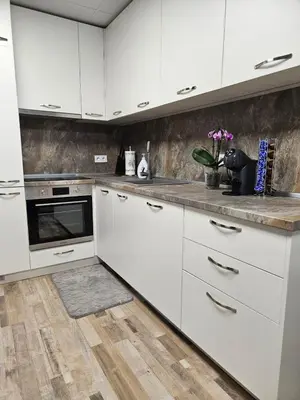 a kitchen with white cabinets and a wooden floor at Central Flat, Close to the beach in Burgas City