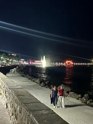 a man and woman walking along a pier at night at Судио Диксан in Pomorie