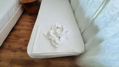 a white pillow with a rose decoration on a bed at ATOS 507 Studio Sunny Beach in Sunny Beach