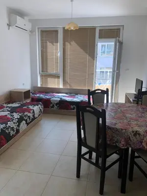 a dining room with a table and two beds at Dobi Apartments in Pomorie